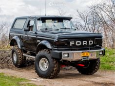 a black ford truck parked on top of a dirt road