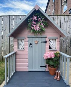 a small pink house with flowers on the front door