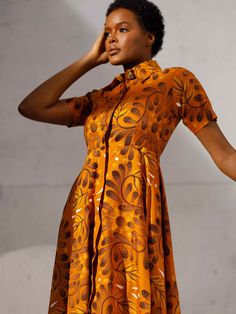 This dress is a testament to our artisans in Nigeria who have meticulously handcrafted fabric sourced from Lagos markets into a garment that transcends fashion and becomes an expression of individuality and a force for good. Fabric: Lightweight non-stretch crisp weave Collared neckline and button placket Short sleeves Floral print On-seam side pockets Shell: 100% cotton Unlined Care: Hand or machine wash in cold water. Do not bleach. Tumble dry low. Fit: True to size As with all our products, ev Fitted Orange Cotton Dress, Orange Cotton A-line Dress, Orange A-line Cotton Dress, Fitted Orange Cotton Midi Dress, Brown Fitted Cotton Dress, Casual Brown Cotton Dress, Orange Fitted A-line Dress, Fitted A-line Orange Dress, A Force