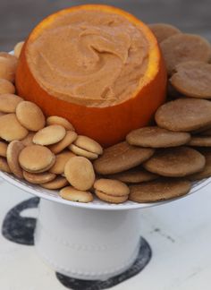 an orange is sitting on top of some cookies and peanut butter dip in a white bowl