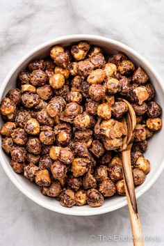 a white bowl filled with candied hazelnuts and a wooden spoon in it