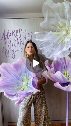 a woman standing in front of flowers with the words here is giani's diy