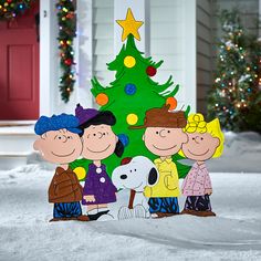 a group of people standing in front of a christmas tree with a dog on it