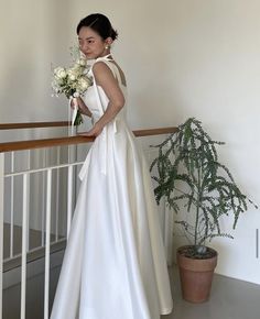 a woman in a white wedding dress standing on a balcony holding a bouquet of flowers