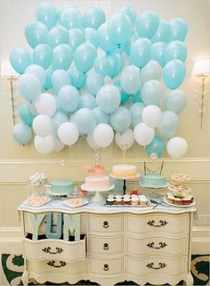 a bunch of balloons that are on top of a table with cake and cupcakes