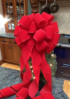 a large red bow on top of a table next to a christmas tree in a kitchen