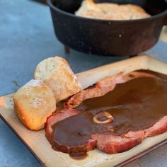 a piece of meat on a cutting board next to some bread and other food items