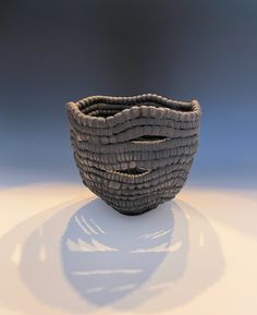 a brown basket sitting on top of a white table next to a black object in the background