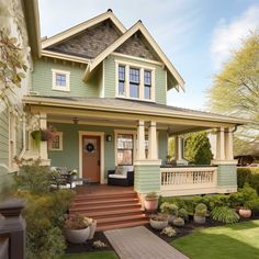 a green house with white trim on the front porch and steps leading up to it