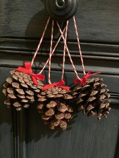 a pine cone wreath hanging from a door with twine of red ribbon on it