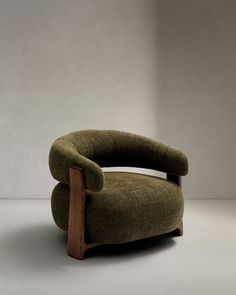 a green chair sitting on top of a white floor next to a wall with a wooden frame