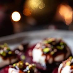 three desserts are sitting on a plate and one is covered in icing, the other has pistachio