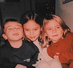 three children are posing for the camera with their arms around each other and one child has his eyes closed