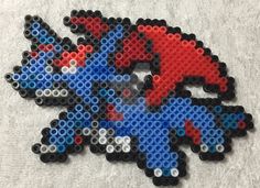 a piece of art made out of legos on a white surface with red, blue and black colors