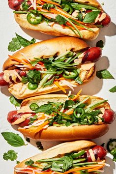 three hot dogs with different toppings are lined up on a white surface and placed next to each other