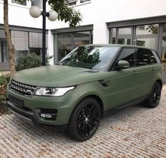 a green range rover parked in front of a building