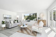 a living room filled with furniture next to a window covered in plants and greenery