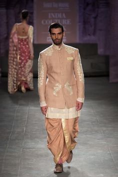 a man walking down the runway in a beige outfit