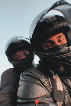 two people wearing helmets are posing for the camera with their arms wrapped around each other