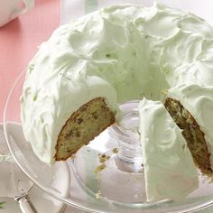 a cake with white frosting on top sitting in a glass dish next to a cup