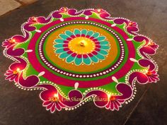 a colorful rangdi design with candles on the ground