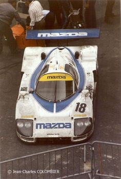 an old race car is parked on the side of the road in front of some people