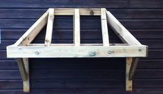 a wooden bed frame sitting on top of a floor next to a blue wall with writing underneath it