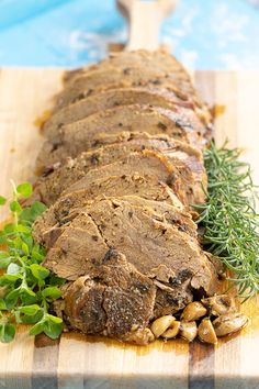 sliced up meat on a cutting board with herbs