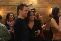 a group of people standing next to each other in a room with exposed brick walls