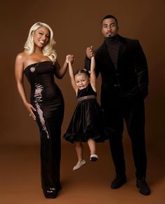 a man, woman and child posing for a photo in black outfits with one holding the other's hand