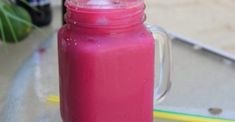 a pink drink in a mason jar sitting on a table next to a yellow pencil