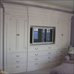 an entertainment center in the corner of a room with white cabinets and drawers on each side