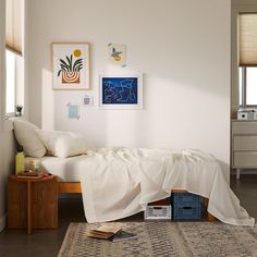 a bed with white sheets and pillows on top of it in a room next to a dresser