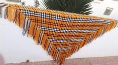 a yellow and black plaid blanket hanging on a white wall next to a palm tree