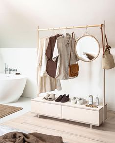 an open closet with shoes and clothing hanging on the rack next to a bathtub