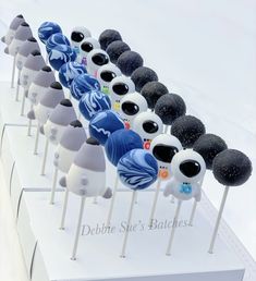 there are many different types of cake pops on the white trays with black and blue frosting