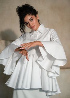 Sesta is a designer cruise blouse-dress, crafted from luxurious 100% cotton gabardine. Feel comfort with its exceptional breathability, even in sweltering heat. Fitted White Blouse With Pleated Sleeves, Elegant Long Sleeve Shirt Dress With Ruffles, Elegant Long Sleeve Ruffled Shirt Dress, Classic White Fitted Shirt Dress, Classic Fitted White Shirt Dress, White Bell Sleeve Formal Dress, White Ruffled Shirt Dress For Work, Chic White Ruffled Shirt Dress, Chic White Shirt Dress With Ruffles