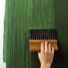 a person using a brush to paint a wall with green grass on the outside and inside