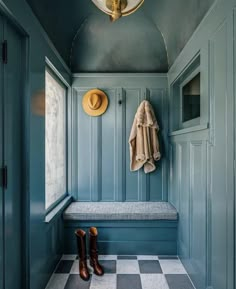 a blue room with a bench, coat rack and hat hanging on the wall next to it