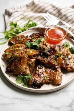 a white plate topped with chicken wings and garnished with cilantro sauce