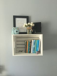 a white shelf with books and pictures on it