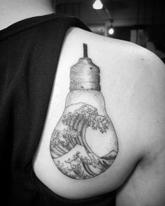 a person with a tattoo on their shoulder that has a light bulb in the shape of a wave