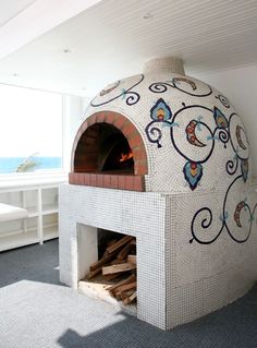 an outdoor pizza oven in the corner of a room with a large window looking out onto the ocean