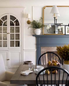 the dining room table is set with plates, glasses and fruit in front of an ornate china cabinet