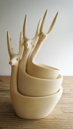 four white ceramic bowls stacked on top of each other with deer heads sticking out of them