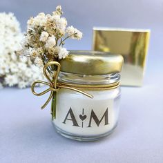 a jar with some flowers in it next to a gold plated object on a table