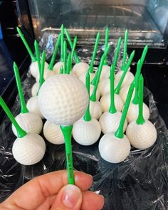 a hand is holding several golf balls and green tees