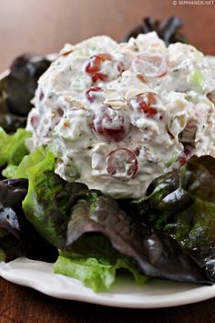 a white plate topped with lettuce and cranberry salad on top of a wooden table