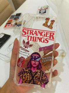 a person holding up a phone case with stickers on it