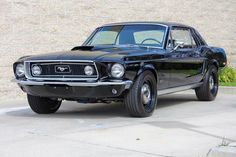 an old black mustang parked in front of a building